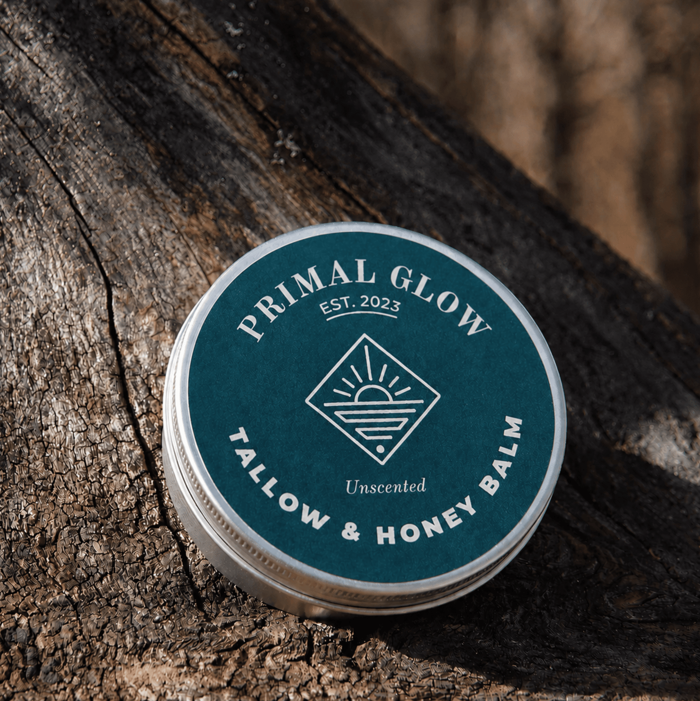 Primal Glow tallow en honing hydraterende balsem van 15 ml op een houten ondergrond met zichtbaar logo.