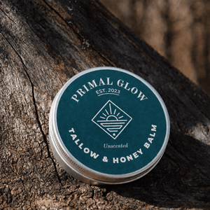 Primal Glow tallow en honing hydraterende balsem van 15 ml op een houten ondergrond met zichtbaar logo.